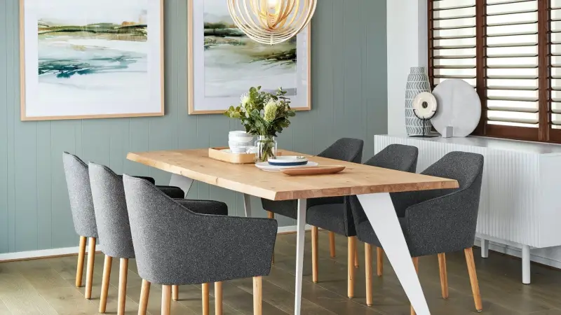 bàn ăn gỗ sồi với chân kim loại màu trắng trong phòng ăn với bức tường màu xanh lá cây xô thơm